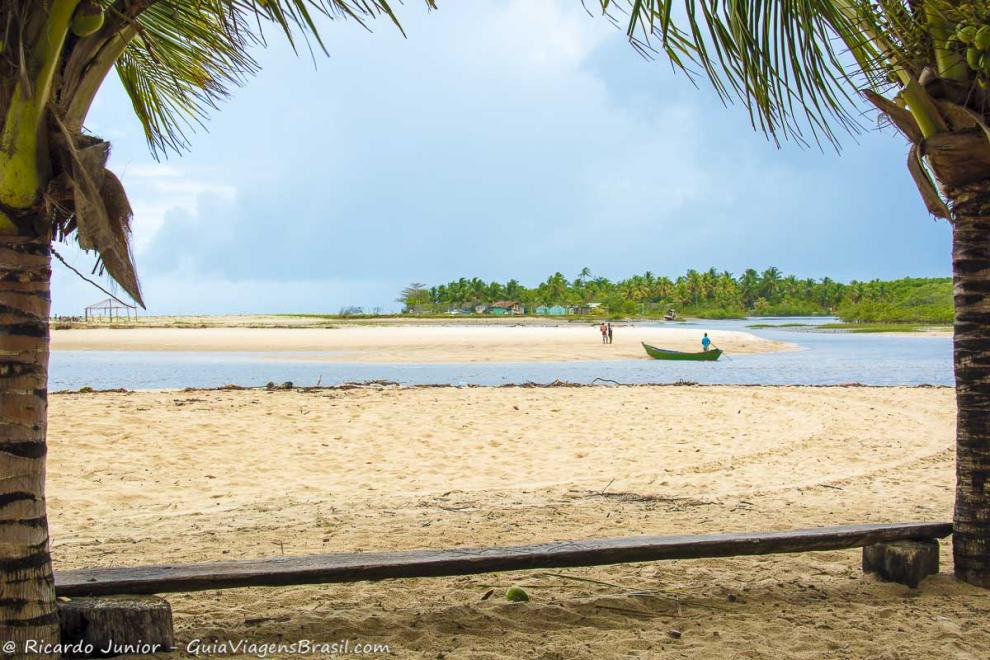 Imagem de banco de madeira entre dois coqueiros na Praia Corumbau.